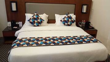 A hotel room with a large bed, two nightstands, a headboard, and a patterned bedspread.