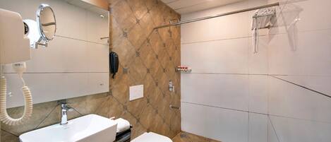 A bathroom with a marble wall, a white sink, a toilet, and a glass shower enclosure.