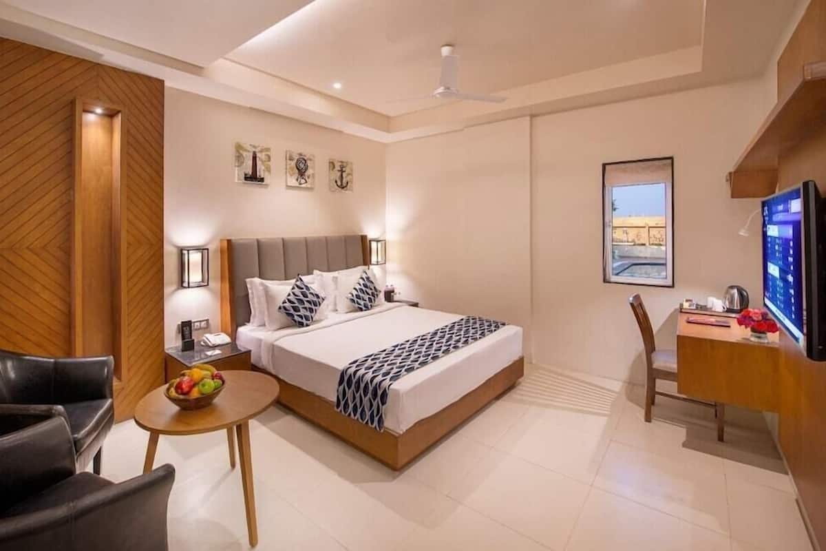 Et moderne hotelværelse med seng, sengebord, lampe og et skrivebord med stol.