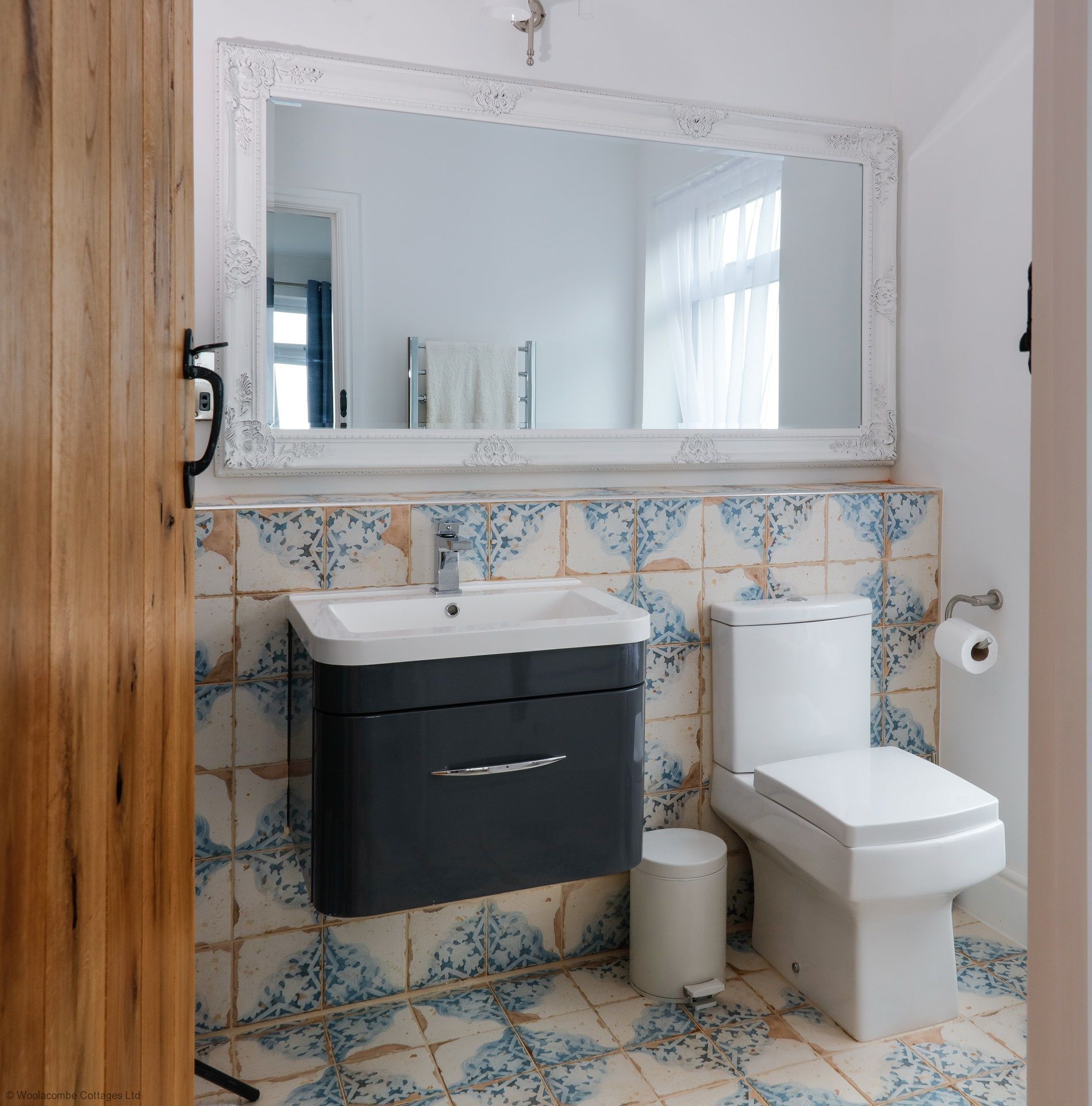 A bathroom with a white sink, black cabinet, white toilet, and a mirror above the sink.