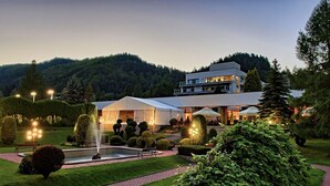 Un hotel moderno con un amplio espacio de comedor al aire libre, una fuente y jardines cuidados.