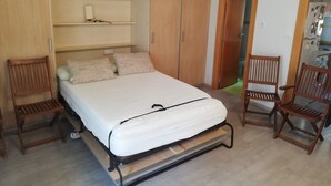 A bedroom with a bed, wooden wardrobe, two wooden chairs, and a ceiling fan. - Estudios Solmar 1º, Solo Familias! (Playa de Gandía)