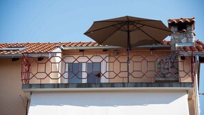 Uma casa com telhado ladrilhado, um guarda-sol grande e uma garagem.