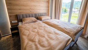 Ein Doppelbett mit beige farbenen Bettwaren, ein Holz-Kopfteil und ein Nachttisch mit Lampe.