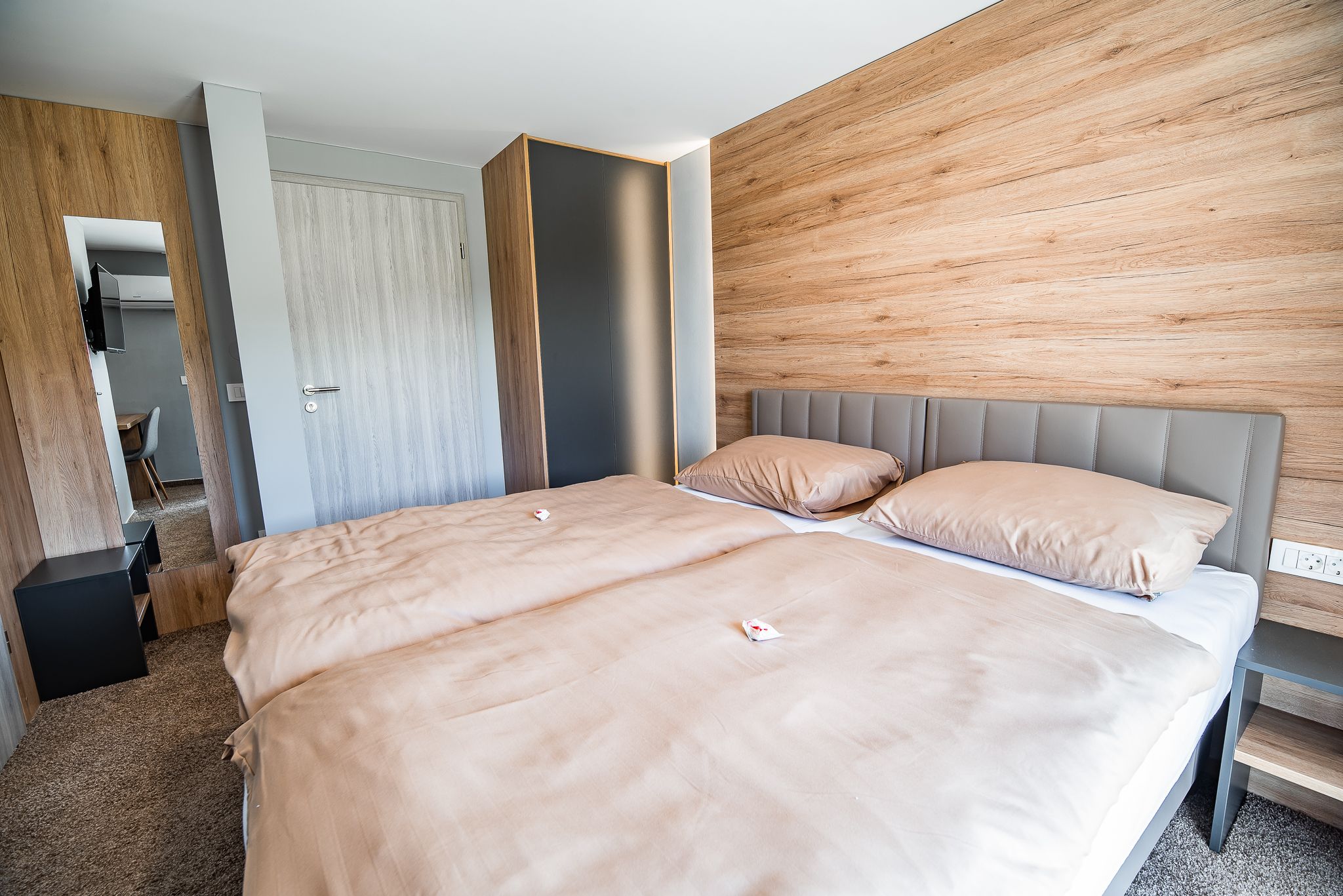 A modern bedroom with a large bed, a wooden headboard, and a built-in wardrobe.