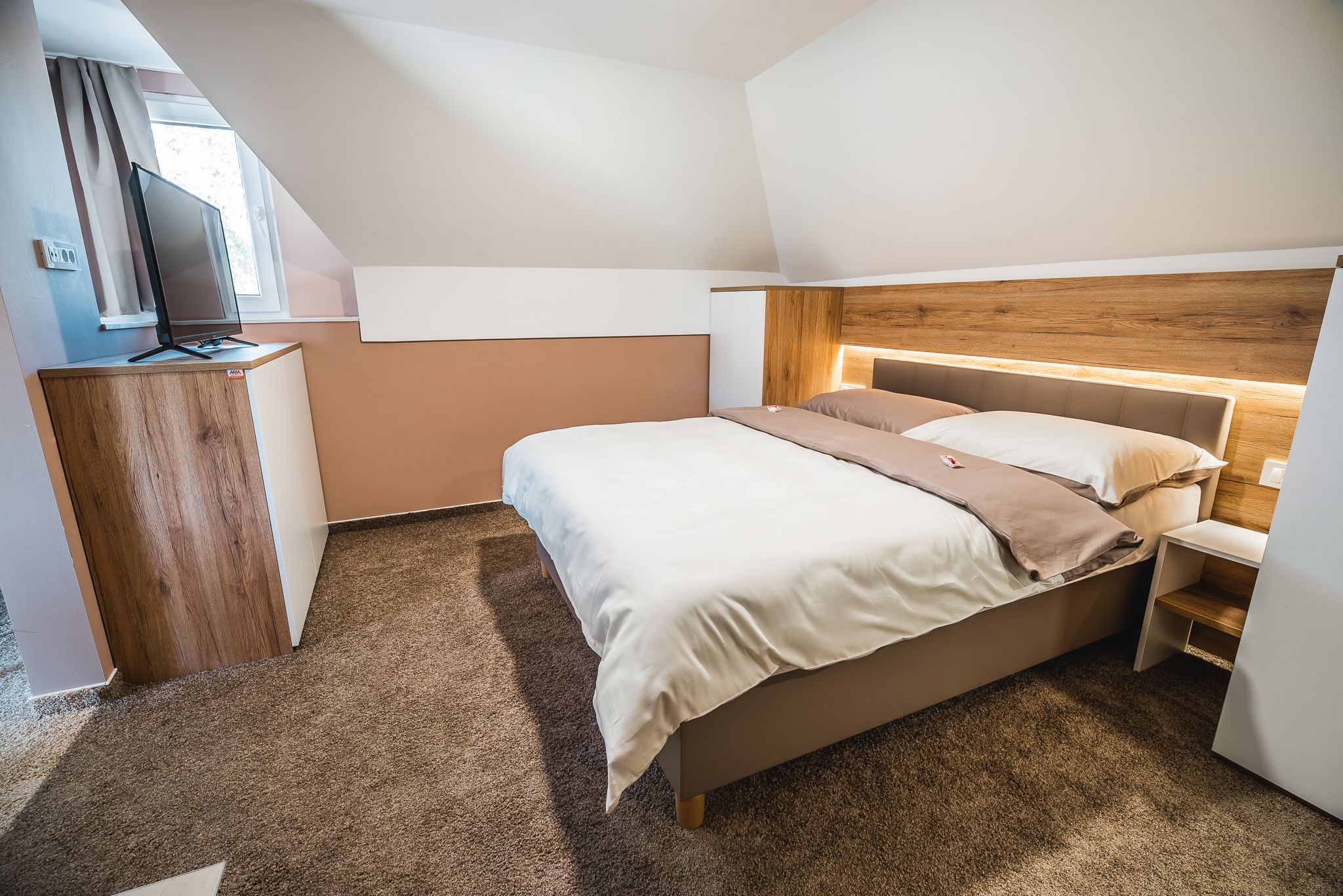 Un dormitorio con cama, cabecera de madera, escritorio y televisor.