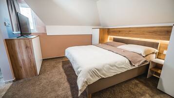 Un dormitorio con cama, cabecera de madera, escritorio y televisor.