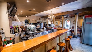 Eine Bar mit einer langen Holztresen, Barhocker und einem Kühlschrank.