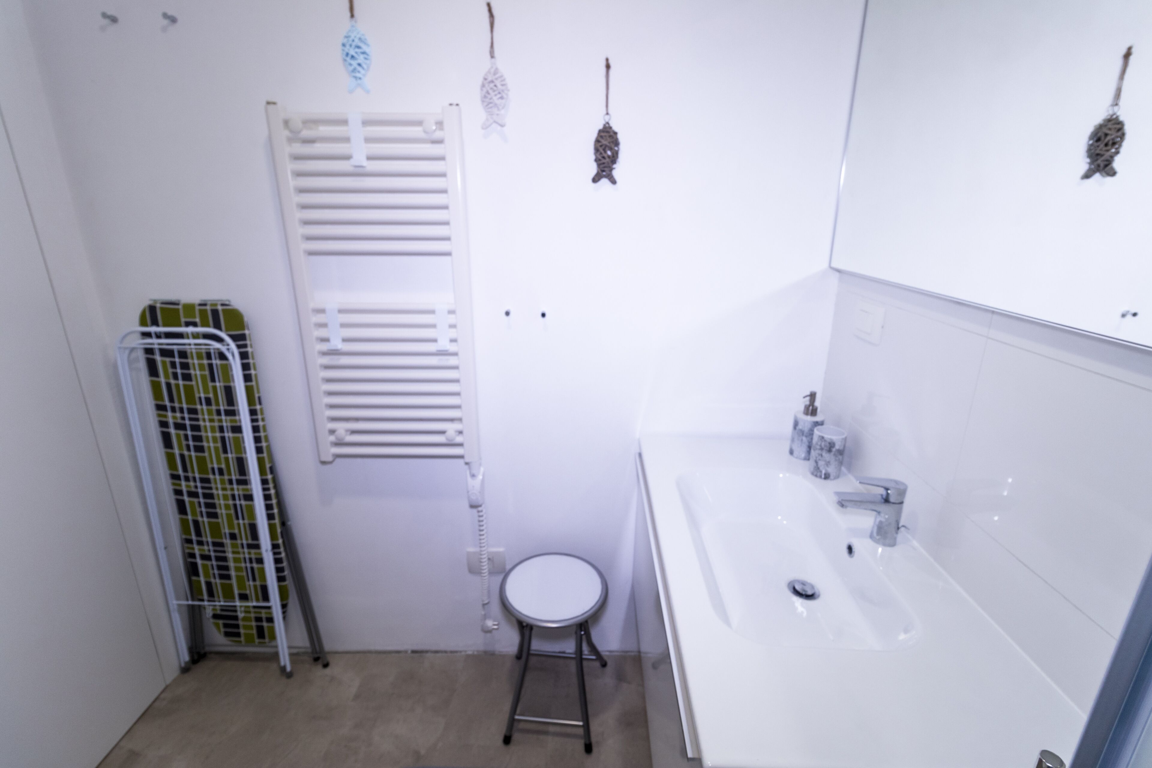 A small, white bathroom with a sink, toilet, and a towel rack.