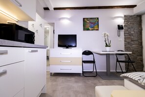 A modern kitchen with a microwave, a TV, and a stone accent wall. - Apartments Bella Tara (Piran)