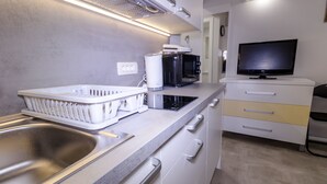 Een moderne keuken met een roestvrijstalen spoelbak, een magnetron, een broodrooster en een televisie op een kast.