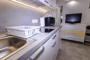 A modern kitchen with a stainless steel sink, a microwave, a toaster, and a television on a cabinet.