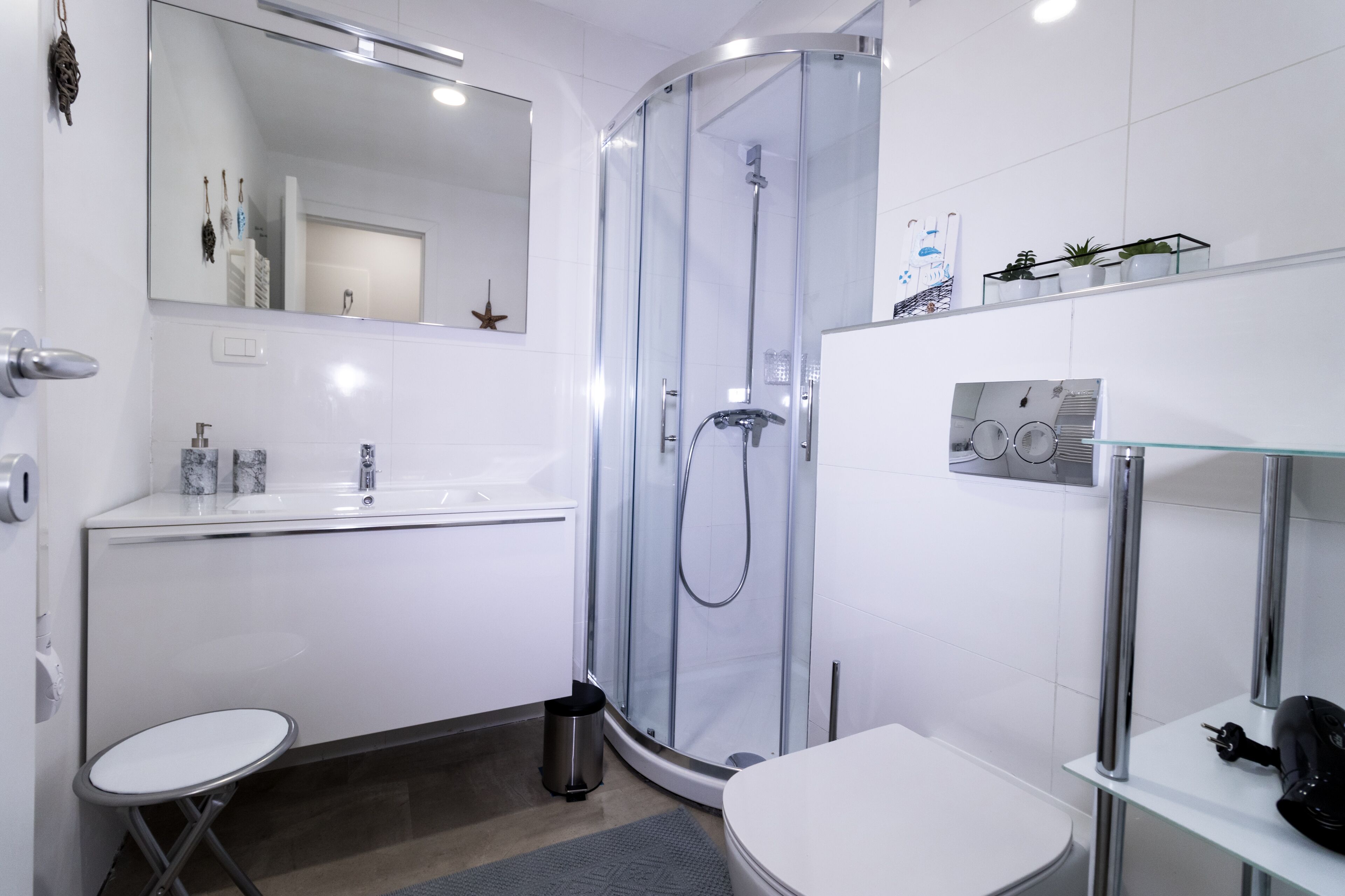 Une salle de bain moderne avec une douche à parois de verre, un lavabo blanc et une petite table ronde.