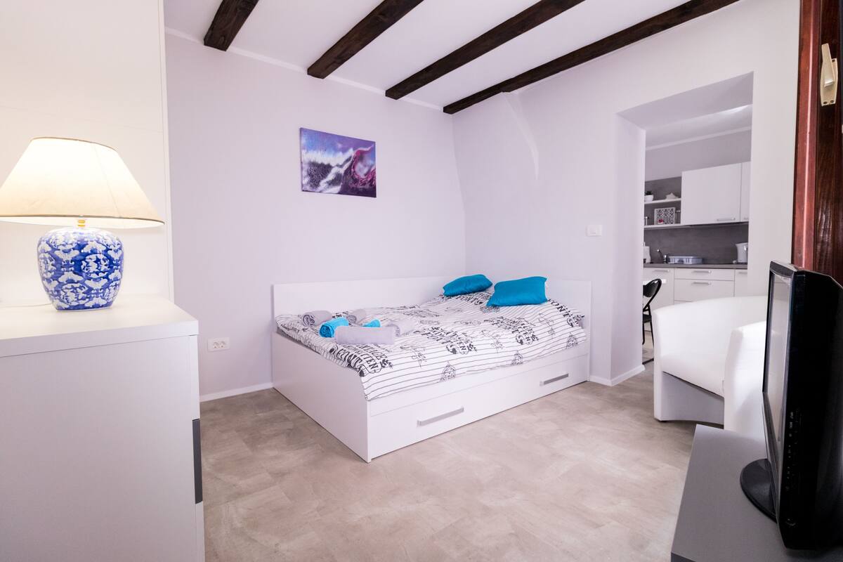 Een slaapkamer met een bed, een bureau, een lamp en een schilderij.