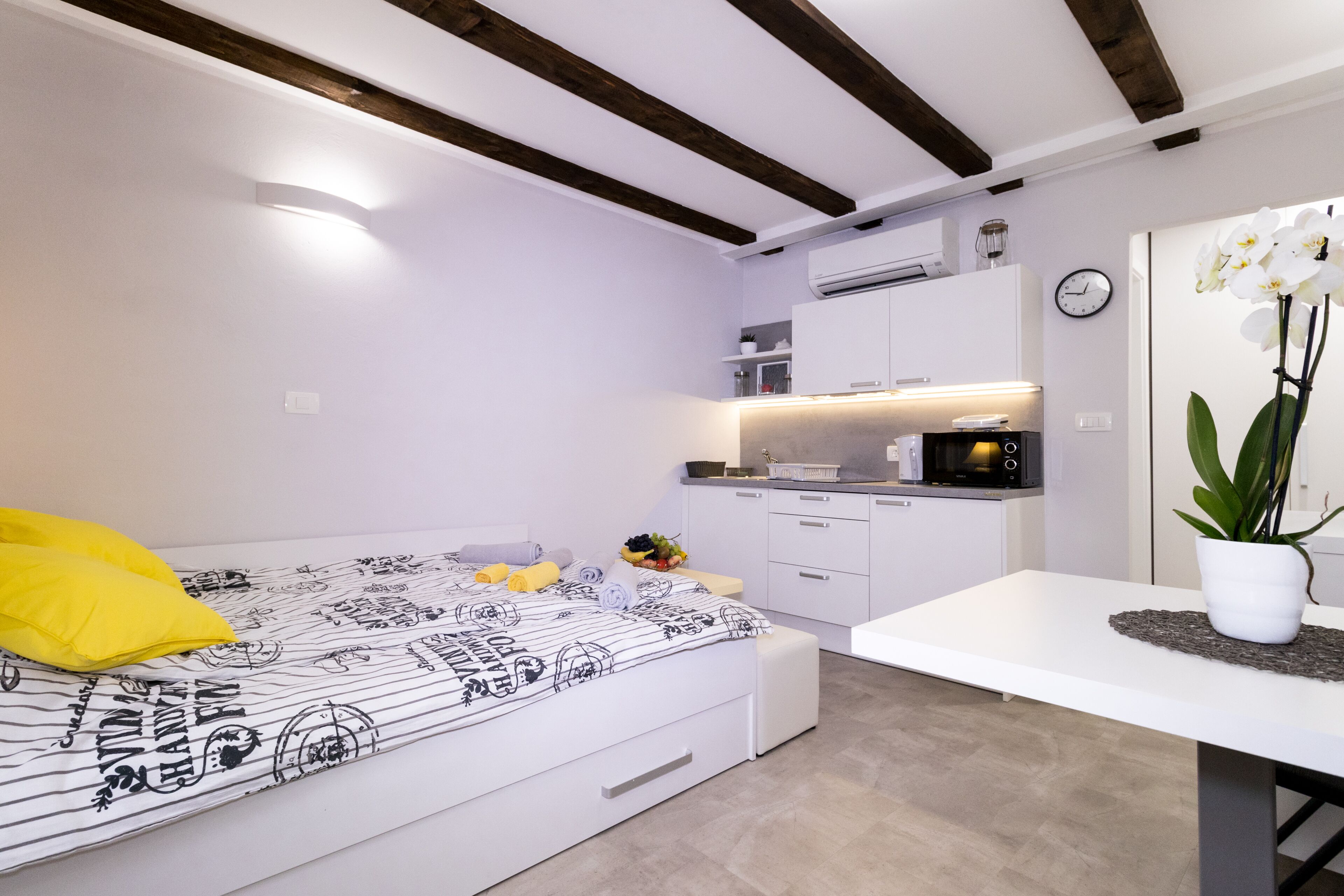 Un dormitorio pequeño con cama, mesita de noche y una kitchenette.