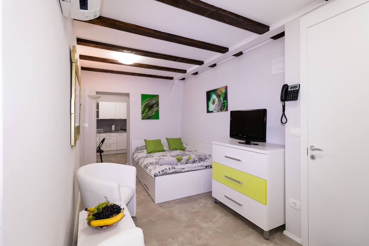 Een slaapkamer met een bed, een televisie, een bureau en een kledingkast.