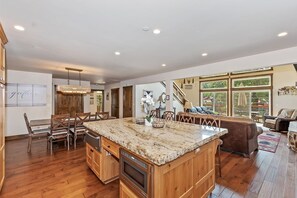 A spacious kitchen with a large island, wooden cabinets, and a dining area with chairs.
