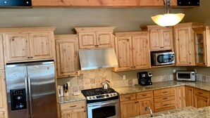 A kitchen with wooden cabinets, stainless steel appliances, and a granite countertop. - McCall Cabin in Spring Mountain Ranch- Shared Pool (McCall)