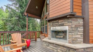 A wooden deck with Adirondack chairs and a stone fireplace. - McCall Cabin in Spring Mountain Ranch- Shared Pool (McCall)