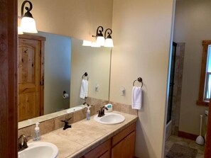 A bathroom with two sinks, a large mirror, and a wooden cabinet. - McCall Cabin in Spring Mountain Ranch- Shared Pool (McCall)