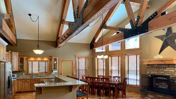 A spacious kitchen with wooden beams, a dining area with chairs, and a fireplace. - McCall Cabin in Spring Mountain Ranch- Shared Pool (McCall)