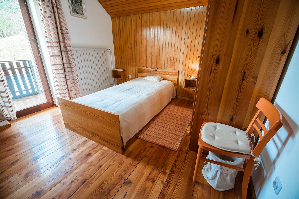 A wooden-paneled bedroom with a bed, a chair, and a radiator.