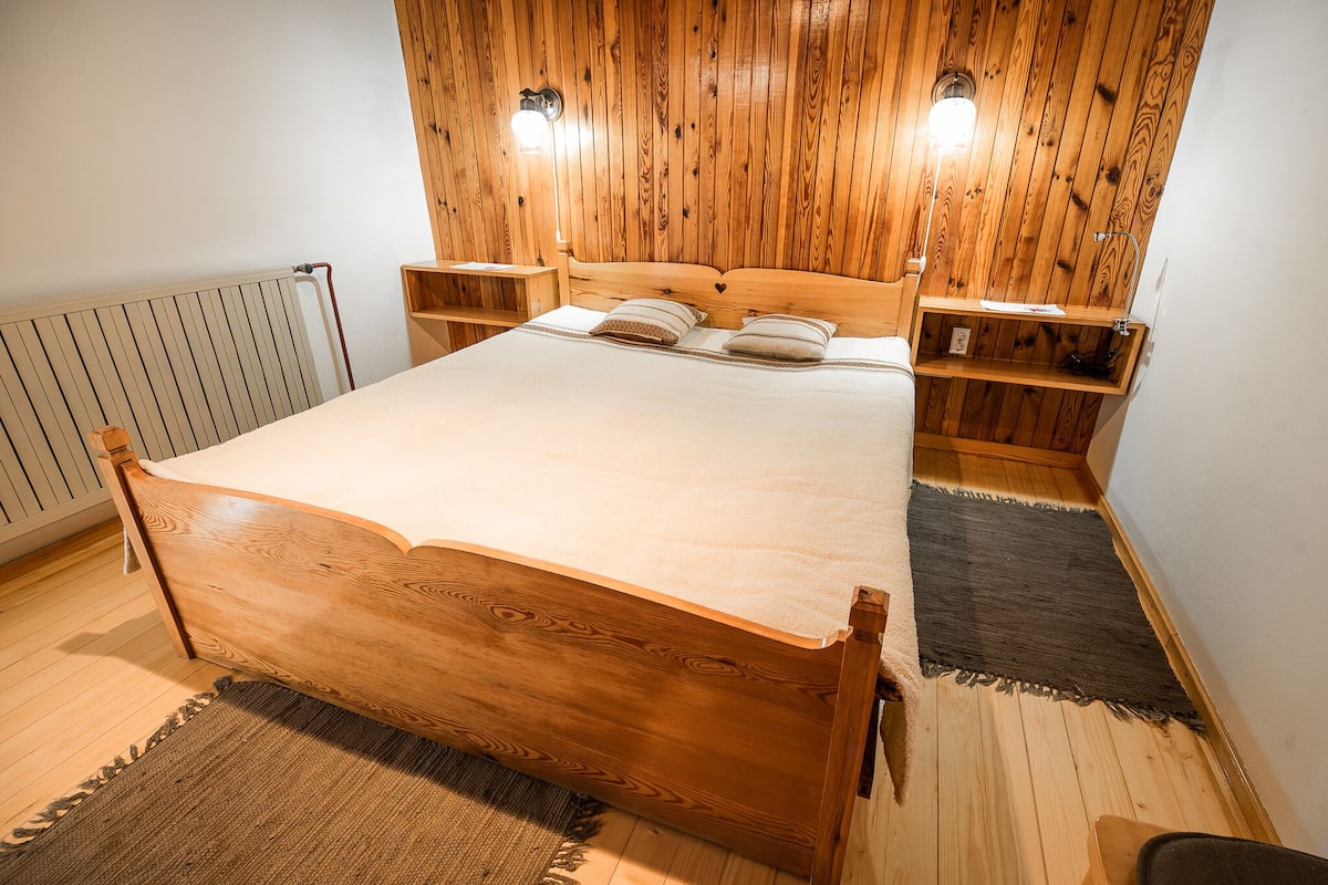A wooden bed with a headboard, two bedside tables, and a nightstand.