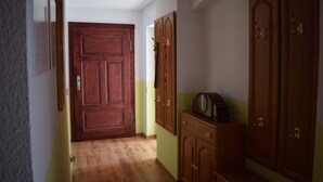 A hallway with a wooden door, wooden cabinets, and a small table with a radio.
