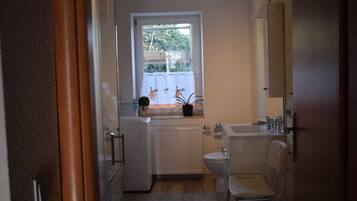 A small, compact bathroom with a toilet, sink, and window.