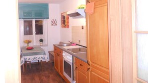A compact kitchen with wooden cabinets, a sink, and a stove.