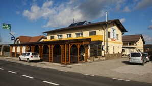 A building with a yellow facade, a covered outdoor seating area, and a sign indicating it is a restaurant.