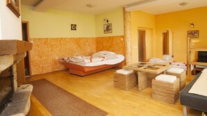 A room with a bed, a small table, wicker ottomans, and a sofa.