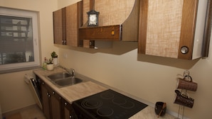 A kitchen with a built-in stove, a sink, wooden cabinets, and a clock on the wall.