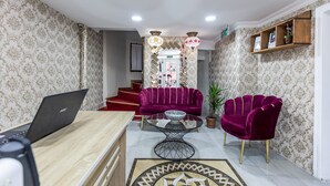 A living room with a laptop on a wooden table, two purple sofas, a coffee table, and a staircase in the background. - OttomanZade (Istanbul)