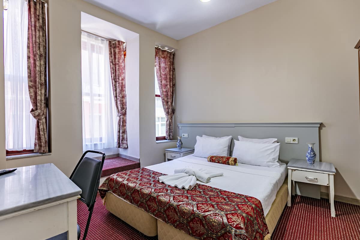 A hotel room with a bed, bedside tables, a desk, and a chair.