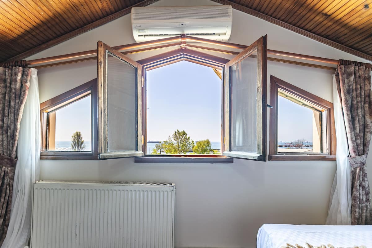A room with a sloped ceiling, a large skylight, a radiator, and a bed.