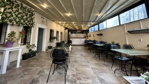 A spacious indoor area with multiple tables and chairs, a kitchen in the background, and large windows allowing natural light. - OttomanZade (Istanbul)