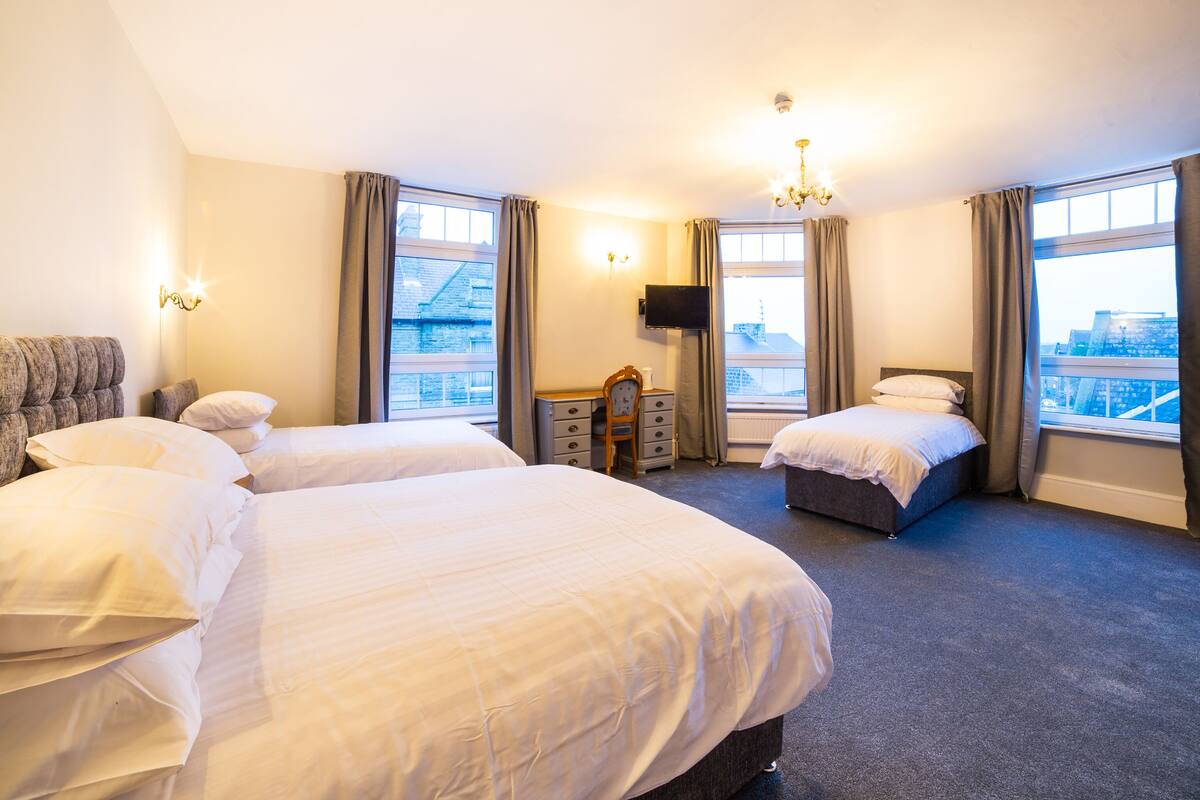A hotel room with two beds, a television, a dresser, and a view of the city.