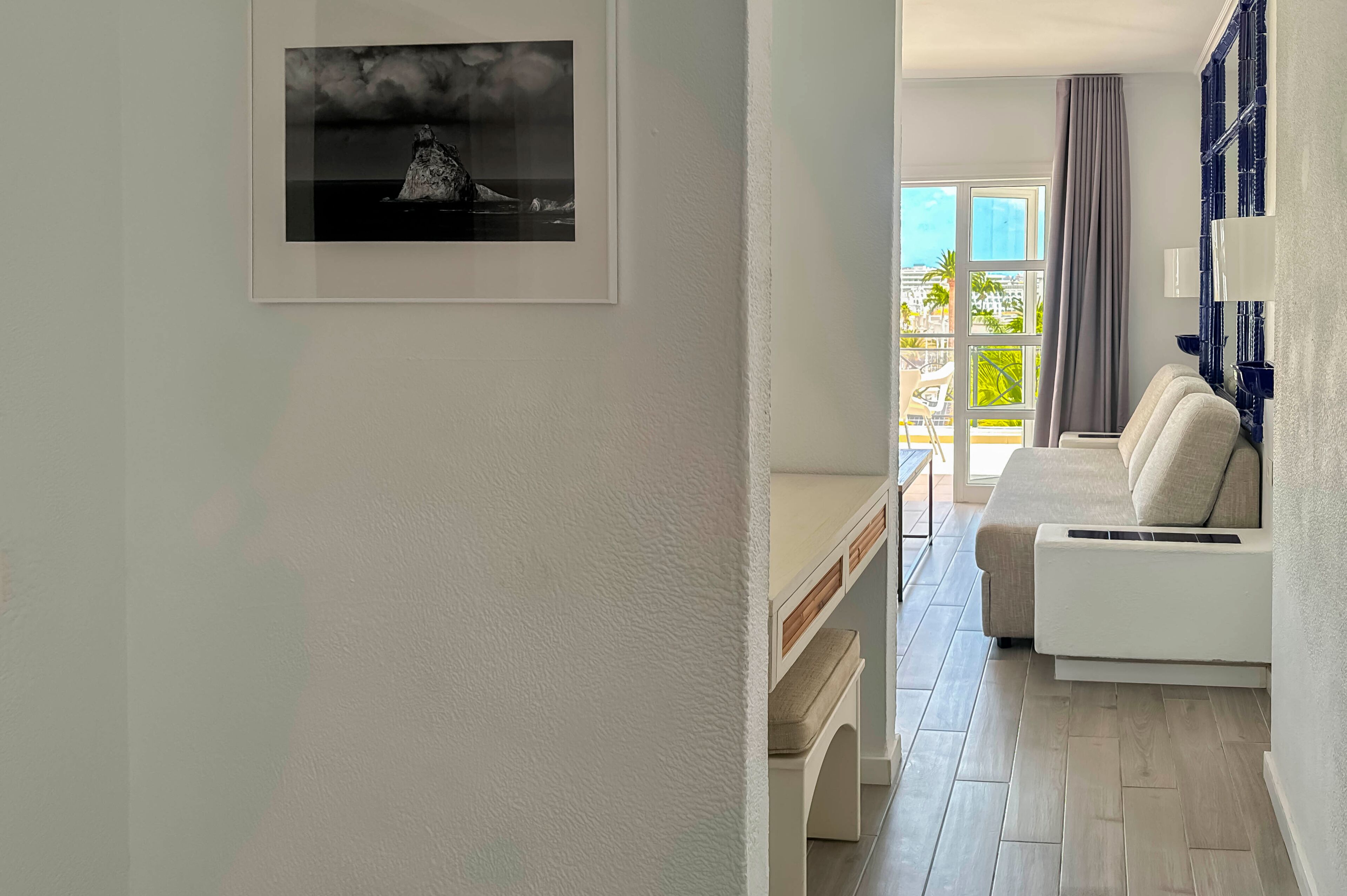A modern living room with a white sofa, a small table, and a framed picture on the wall.