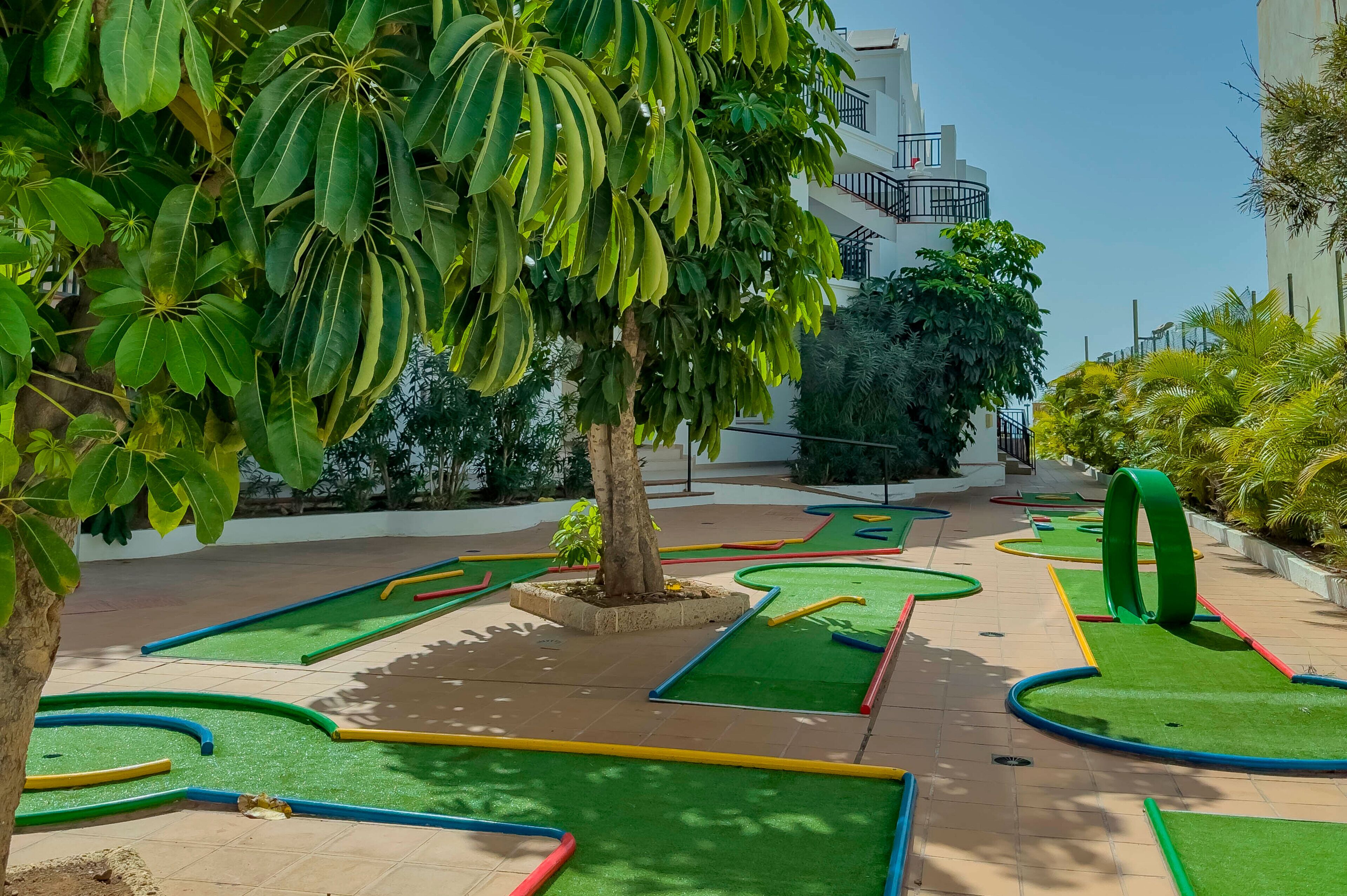 Ein Golfplatz mit grünen Spielbahnen, Sandbunkern und einem Gebäude im Hintergrund.