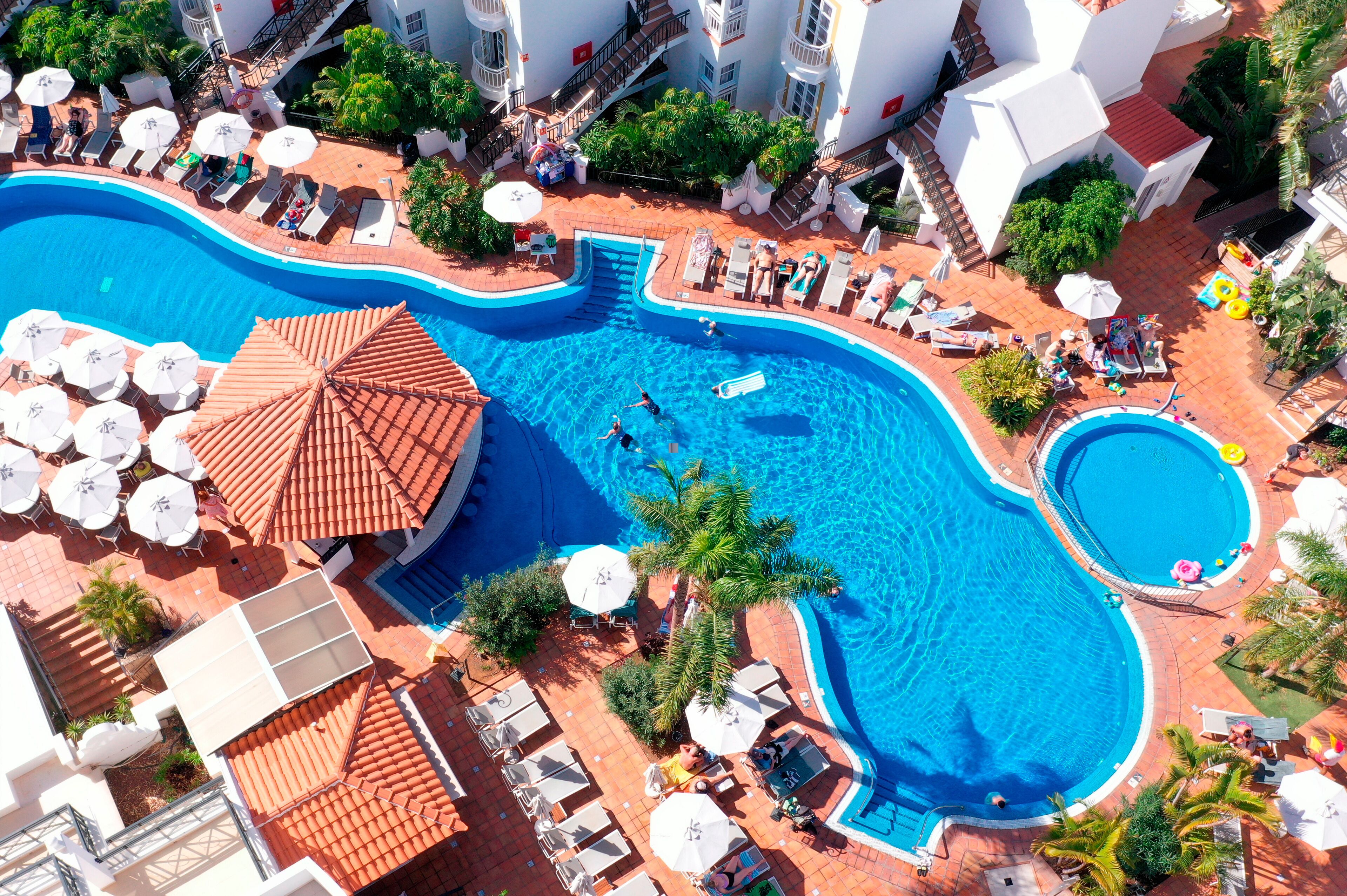 Une grande piscine avec plusieurs couloirs de nage, entourée de chaises longues et de parasols.