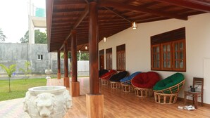 A covered outdoor seating area with wicker chairs and a stone urn.