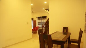 A dining area with a wooden table and chairs, a staircase, and a red chair in the background.
