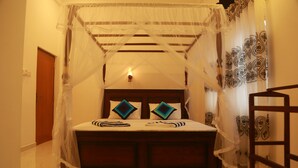 A bedroom with a canopy bed, a wooden headboard, and patterned curtains.