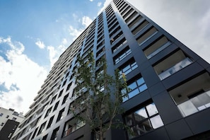 A modern high-rise building with a grid-like facade and multiple windows. - Warsaw | Wolska 45 | Comfortable studio flat | Balcony and air conditioning (Warszawa)