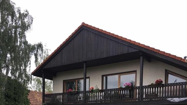 A two-story house with a balcony, surrounded by well-maintained gardens and hedges. - Pension Anna Gastronomie (Loebau)