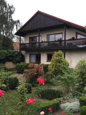A two-story house with a balcony, surrounded by well-maintained gardens and hedges. - Pension Anna Gastronomie (Loebau)