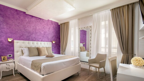 A bedroom with a large bed, a bedside table, a chair, a desk, and a mirror. - I Fiumi Di Navona (Rome)