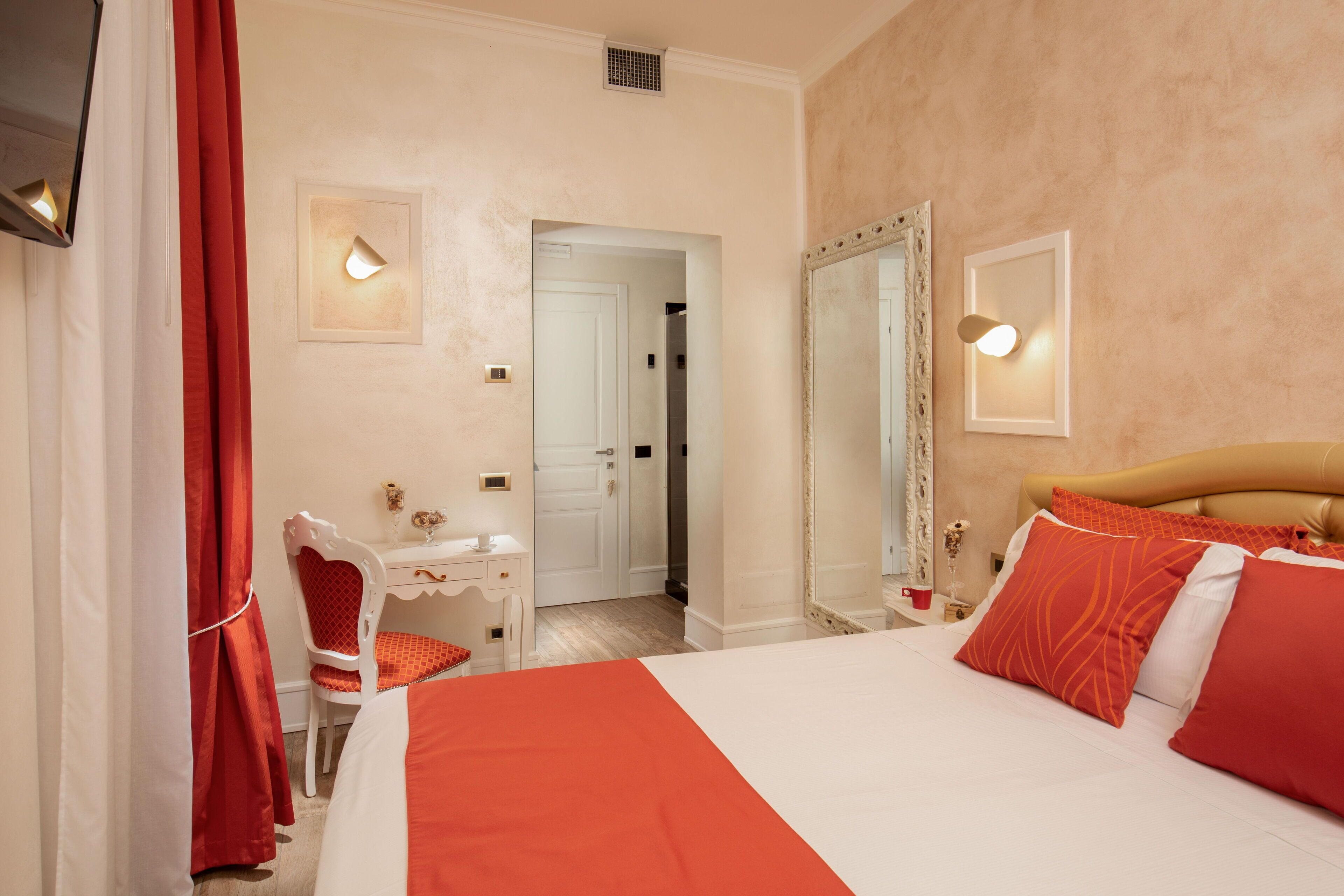 Ein Hotelzimmer mit Bett, Schreibtisch, Stuhl, Spiegel und Tür.