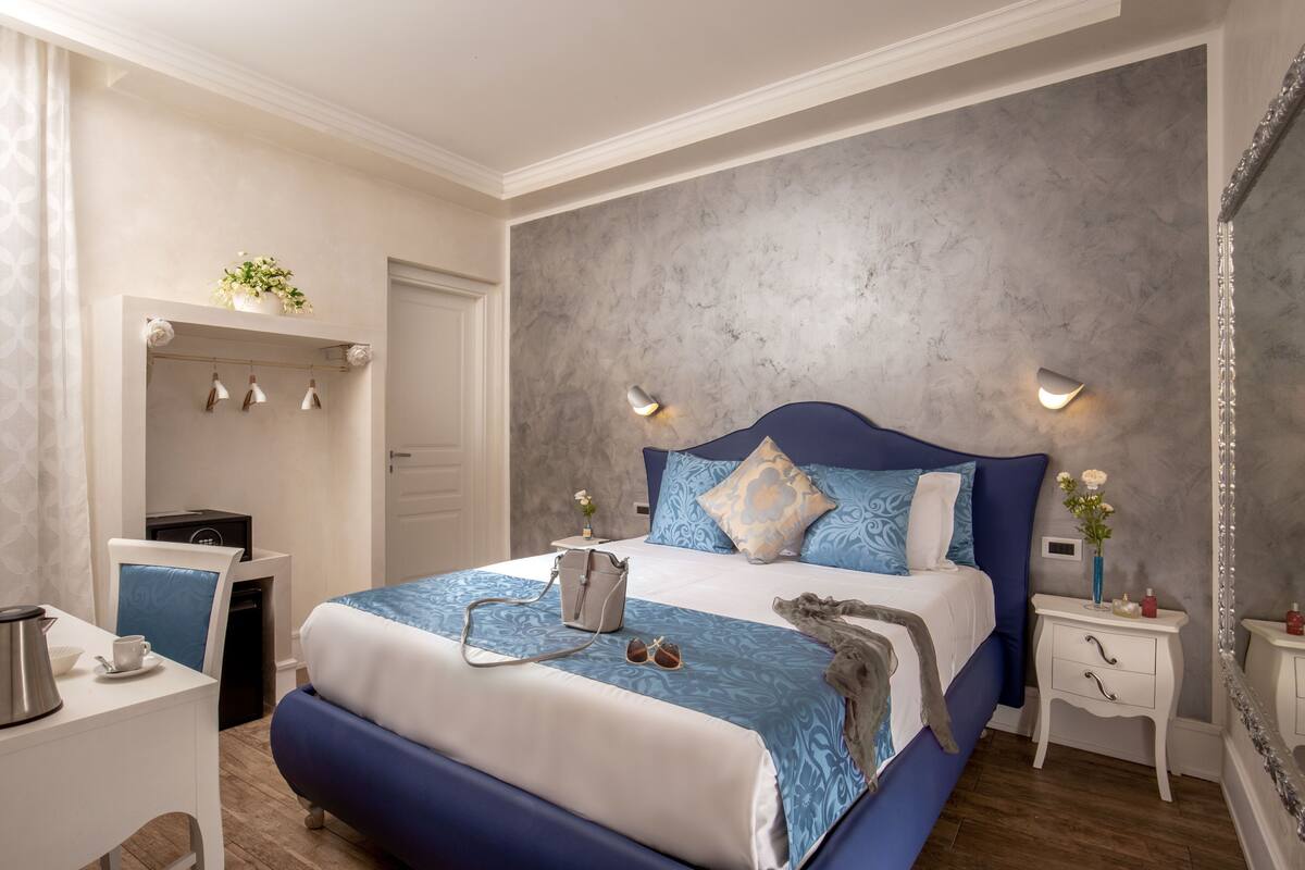 Un dormitorio con cama, mesitas de noche, un escritorio y un espejo.